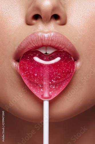 Close up of a Person Holding a Heart Shaped Lollipop in Their Mouth With Glos...