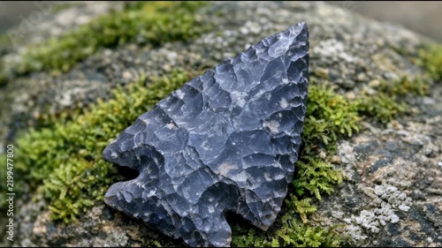 A ancient stone arrow on a rock covered in moss
