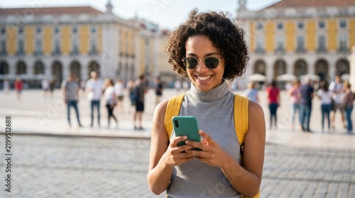 A happy traveler checking her phone in Lisbon, Portugal at the historic Commerce Square.