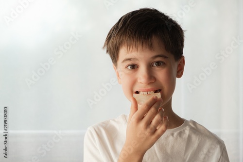 The beautiful caucasian boy holds a dental aligner in his hand near the mouth looking at camera. Orthodontic treatment, dental care, oral hygiene. Teeth alignment. Gap teeth or diastema.