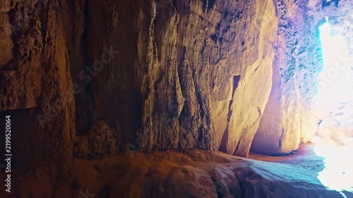 Golden sunrise light shines into the natural sandstone slot cavern of Goblette Lair at Goblin Valley State Park in Utah