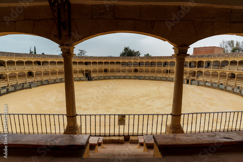 Columned view of the Ronda bullring's sandy arena and tiered stands