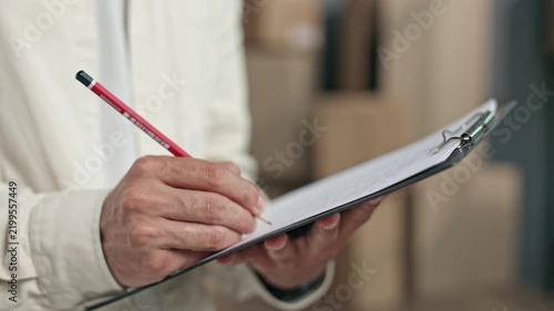 Hand writes on clipboard with red pencil