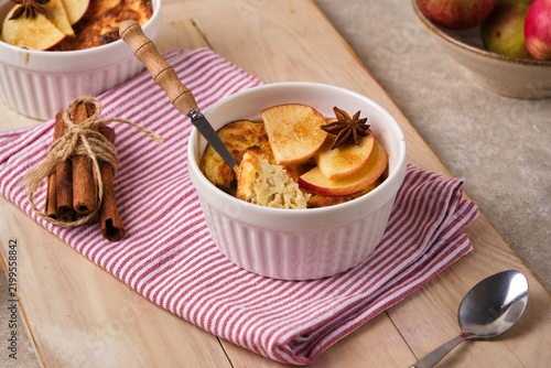 Individually served cottage cheese casserole with apples and brown sugar on a wooden tray against a light concrete background.