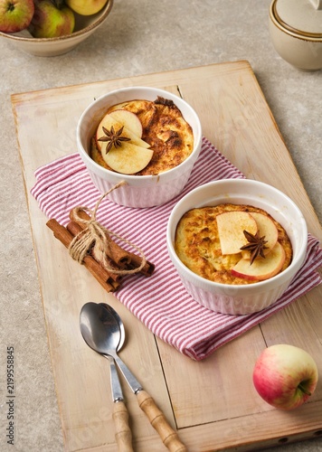 Individually served cottage cheese casserole with apples and brown sugar on a wooden tray against a light concrete background.