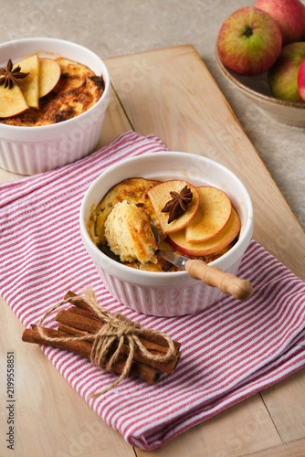 Individually served cottage cheese casserole with apples and brown sugar on a wooden tray against a light concrete background.