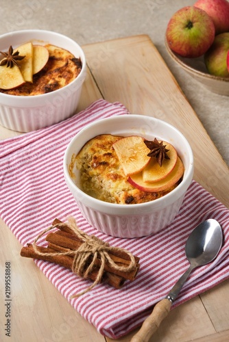 Individually served cottage cheese casserole with apples and brown sugar on a wooden tray against a light concrete background.