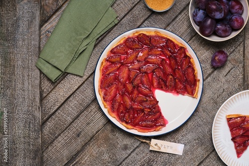 Plum tart on shortcrust pastry on a ceramic plate against a gray wooden background. Plum recipes.