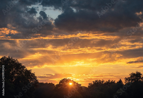 Vibrant Golden Sunset Over a Tropical Beach with Sun Rays and Clouds