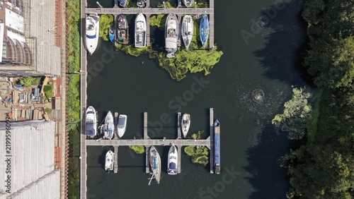 фотографія Top-down aerial photograph of boats moored along floating docks at a marina near Cardiff, Wales, surrounded by dark calm water and green vegetation