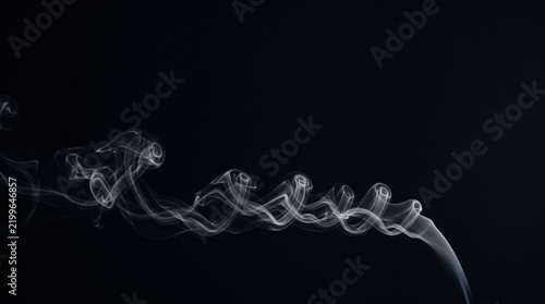 White smoke curls against a dark background creating an abstract form