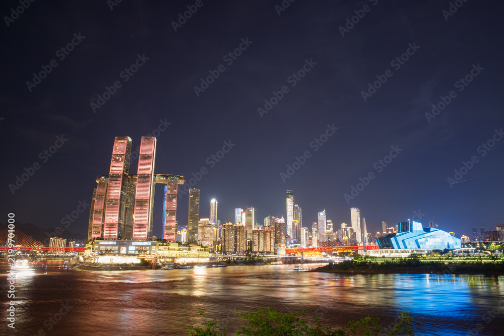 Fototapeta premium Night view of illuminated Raffles City Chaotianmen along riverside in Chongqing, China