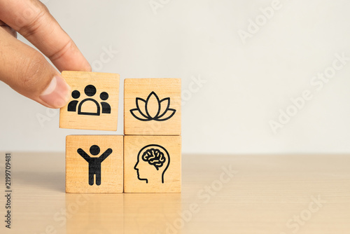 Wooden blocks showing PHYSICAL, MENTAL, SOCIAL and BALANCE icons, Representing well being, work life balance, employee wellness and holistic health concepts.