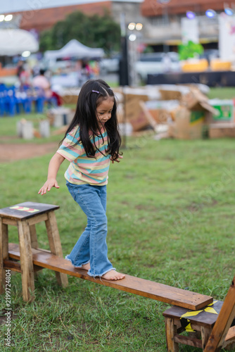 preschool child girl walking on wooden balance beam in park