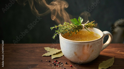 Mug of hot herbal broth standing on a table during cold and flu season
