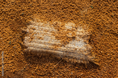 Foto Tattered old fabric piece lying abandoned on coarse desert sand with rough textu