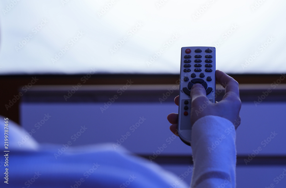 Obraz premium Entertainment and leisure, person holding a television remote control at home while watching movies or streaming media in a dark living room environment