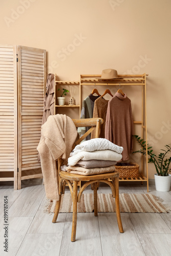 Wooden chair with stack of knitted sweaters in dressing room