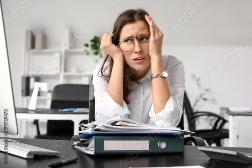Stressed businesswoman searching through files at table in office