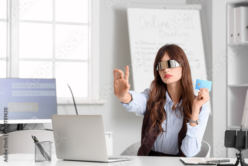 Young businesswoman in AR glasses with credit card and laptop using virtual s...