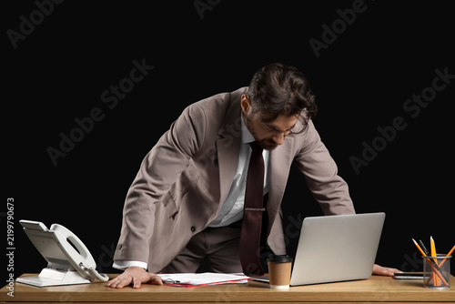 Angry businessman at desk on black background