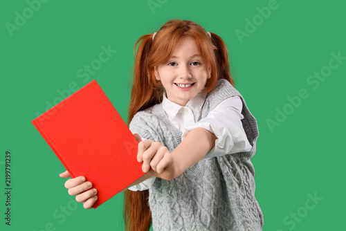 Teenage redhead girl with notebook on green background