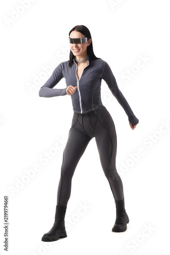 Young woman in futuristic costume with VR glasses on white background