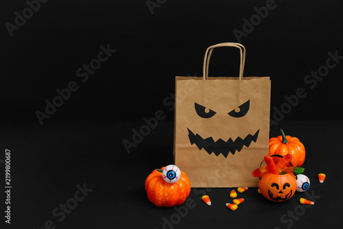 Composition with paper shopping bag, decorations and treats for Halloween on ...