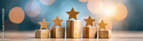 Wooden podiums with sparkling gold stars on top against a blurred background of warm bokeh lights.