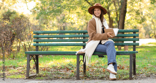Mindfulness and mental health, young woman reading a book on a park bench dur...