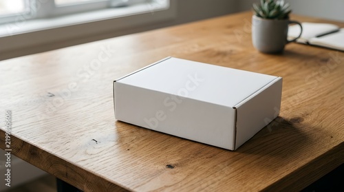 White cardboard mailer box mockup sitting on a wooden office desk with plant and notebook