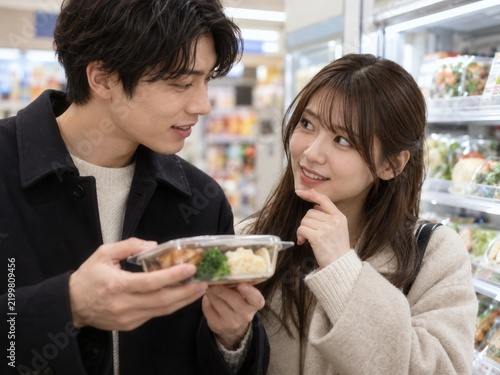 Young Couple Choosing Ready Meal in Supermarket Aisle Together
