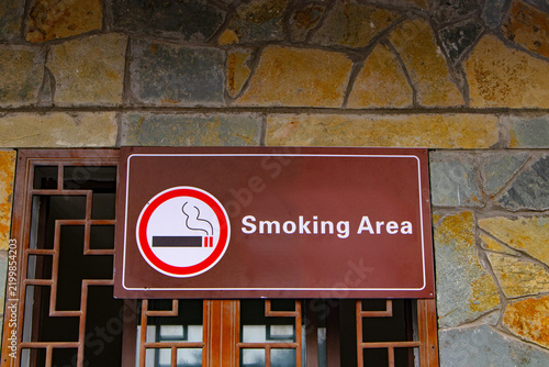 Signs smoking area wood brown with cigarette symbols and icons attached to building wall at entrance to public tourist area. Smoke in designated smoking area. Smoking area sign at public park.