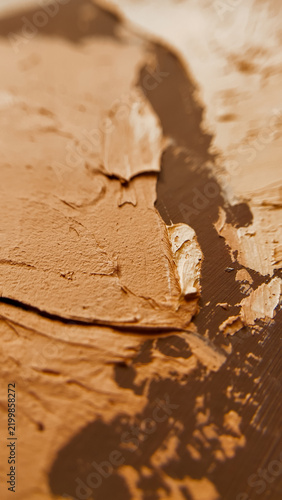 Vertical macro view of textured orange and brown plaster with rough surface details. abstract stucco background, textured wall finish, creative design elements.