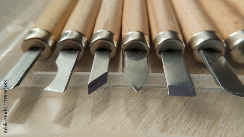 Bild auf Leinwand A side view close up of sharp metal blades of wood carving chisels neatly aligned on a workshop table