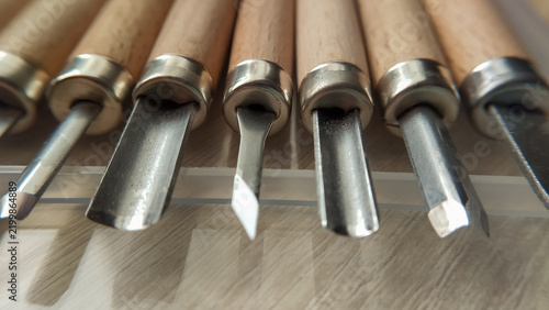 Fotografie Various sharp wood carving chisels with different blade shapes arranged next to each other on a workshop bench