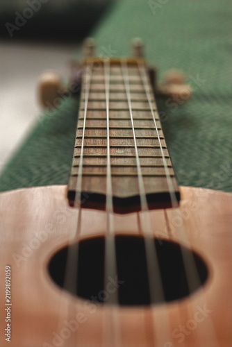 Close-up view of the ukulele's body and strings. Children's guitar. The ukulele, a four-stringed musical instrument. Musical instrument concept. Selective focus. No people, nobody. Vertical photo.
