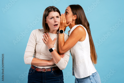Fotografie Woman whispering secret to shocked friend, spreading rumors
