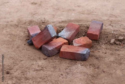 Scattered Red Clay Bricks on Sandy Ground at a Traditional Brick Kiln in Rural India.