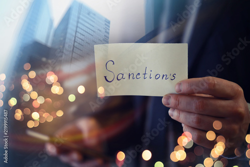 Foto Man showing sanctions word on paper and devastated middle aged caucasian man in
