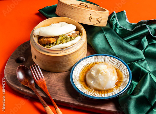 Fotografie Steamed bao bun and savory dumpling served in a bamboo steamer on a wooden board