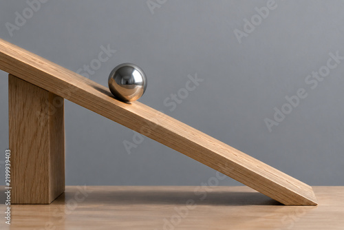 Steel ball on tilted wooden board, inclination and gravity balance concept