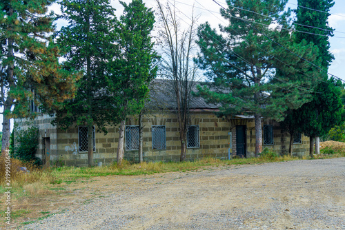 An old, abandoned sulfur bathhouse in the village of Asureti. It's lined with beige and brown tiles, and the windows have iron mesh bars. Surrounded by trees. Asureti, Elizabettali, Georgia