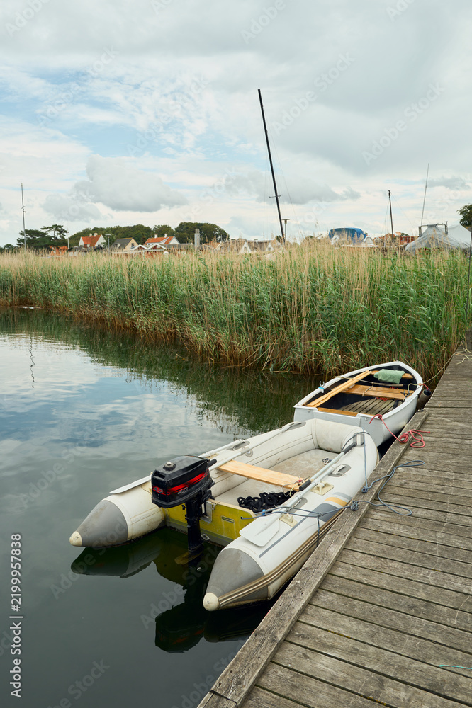 Fototapeta premium Small boats tied to a wooden dock on a quiet river