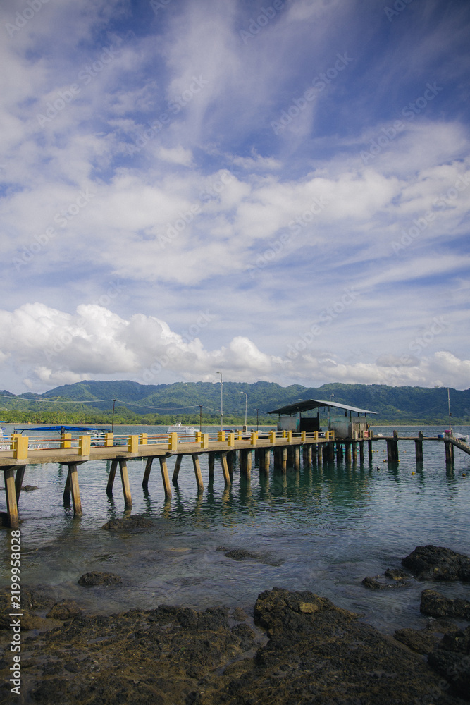 Fototapeta premium Rustic concrete pier over calm water with mountains