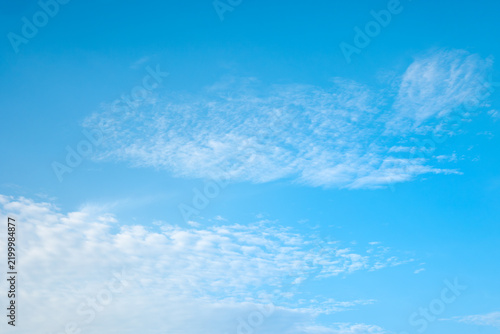 Bright blue sky background with soft white wispy and cirrus clouds floating gently, clear daytime skyscape with ample copy space.