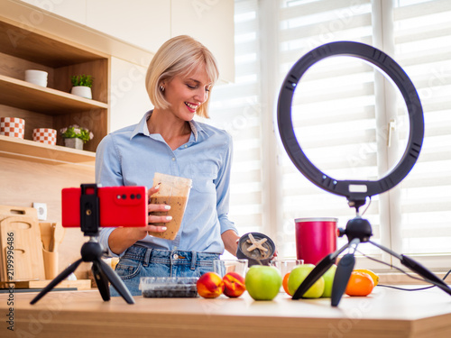 Fresh and healthy recipe creation with a smiling woman preparing a smoothie in her home kitchen.