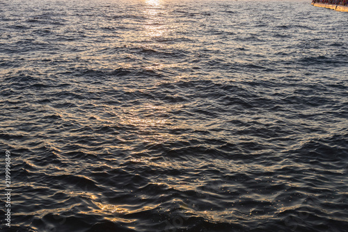 Golden sunset reflection on rippled sea water surface
