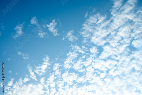 Natural cloudscape featuring dense fluffy cumulus formations floating across an expansive vivid cerulean atmosphere, calming daylight sky background element.