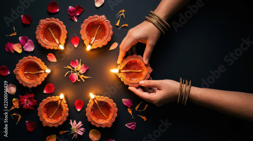 Traditional Diwali celebration viewed from above, with hands lighting clay diyas surrounded by flowers and petals, capturing Indian culture, festive warmth, joy, tradition and the spirit of light